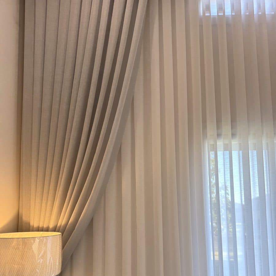 Close-up of a sheer curtain held back beside a lamp